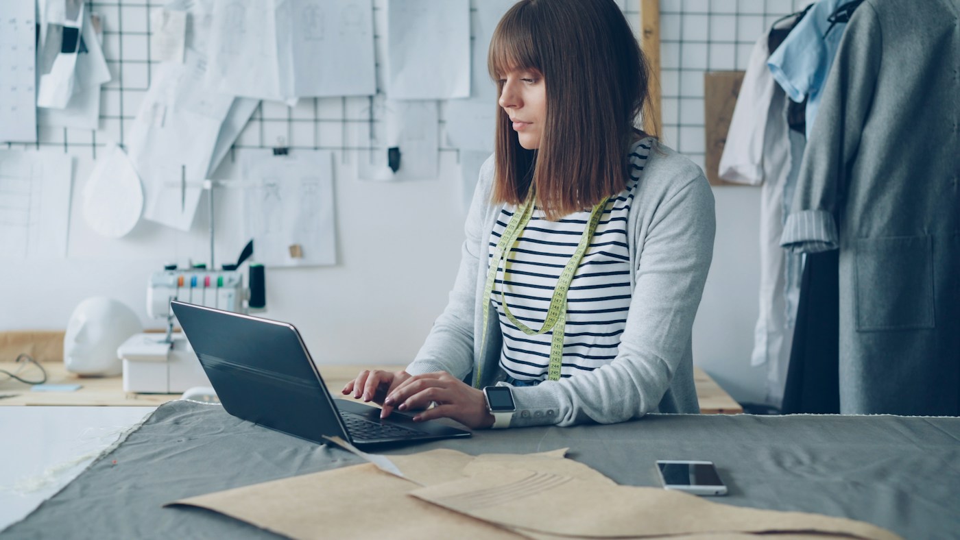 A clothing designer working on her laptop in her studio